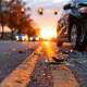 Damaged car after road collision incident on asphalt street with shattered debris at sunset or sunrise traffic lights and blurred background