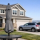 Stock photo of a Highlands Ranch, Colorado home and vehicle, with a closed umbrella symbolizing added liability protection, no people present.