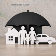 Stock photo of paper cutouts of a house, car, and family protected by an umbrella, representing layered liability insurance coverage for Highlands Ranch homeowners in Colorado.